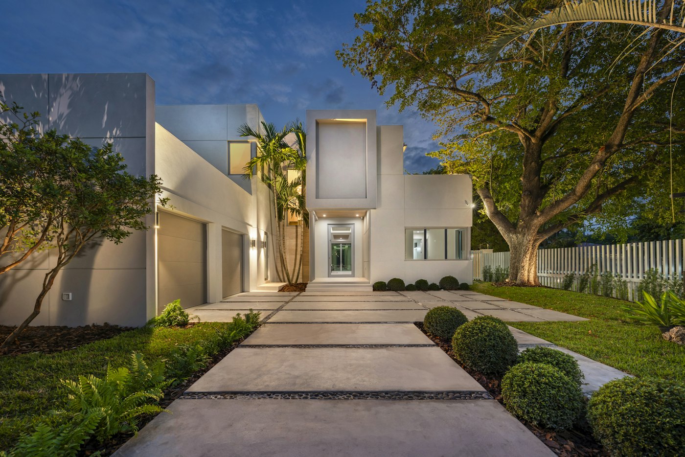 Allée éclairée menant à une maison moderne au crépuscule