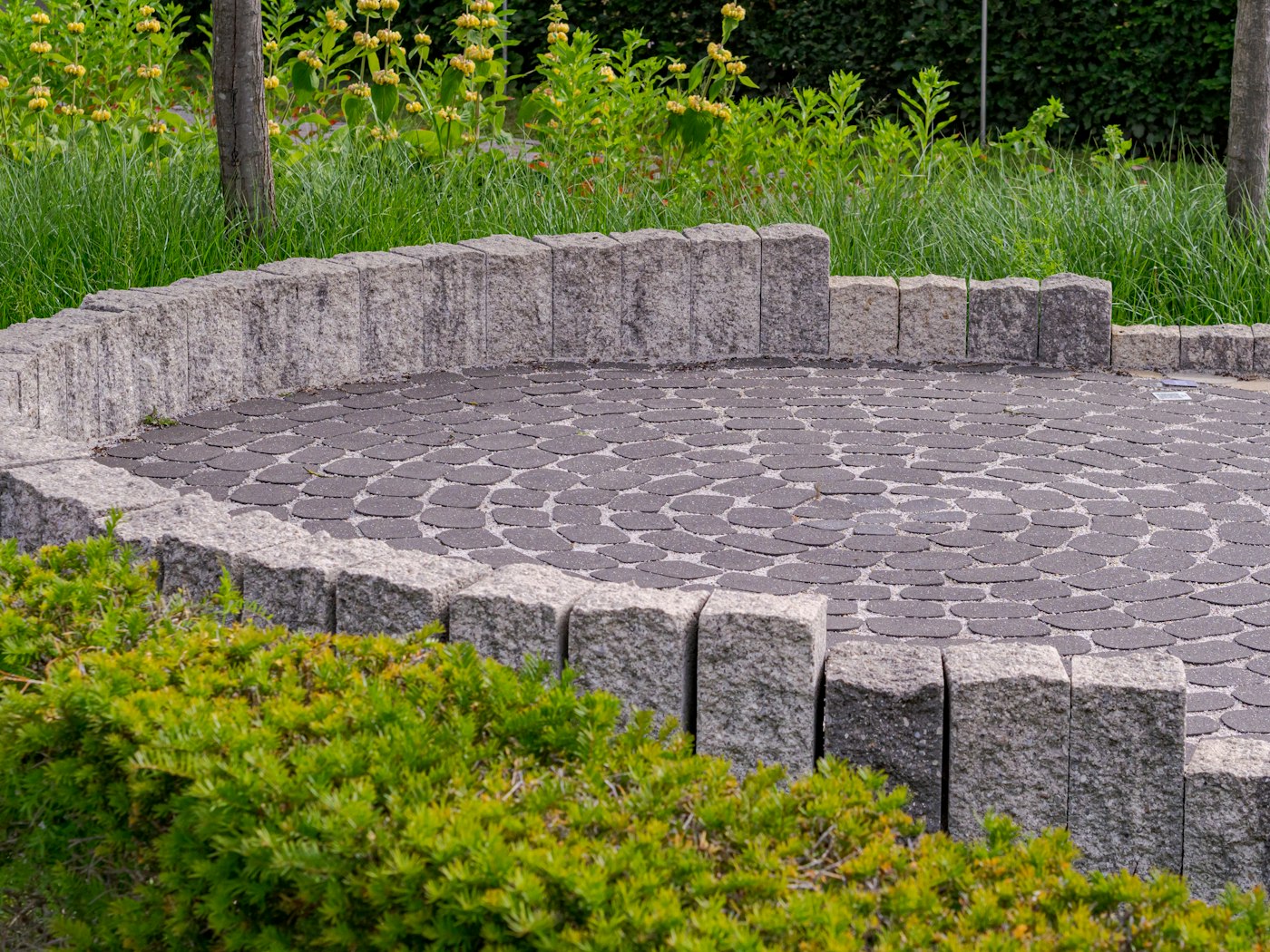 Terrasse circulaire pavée entourée d'un muret